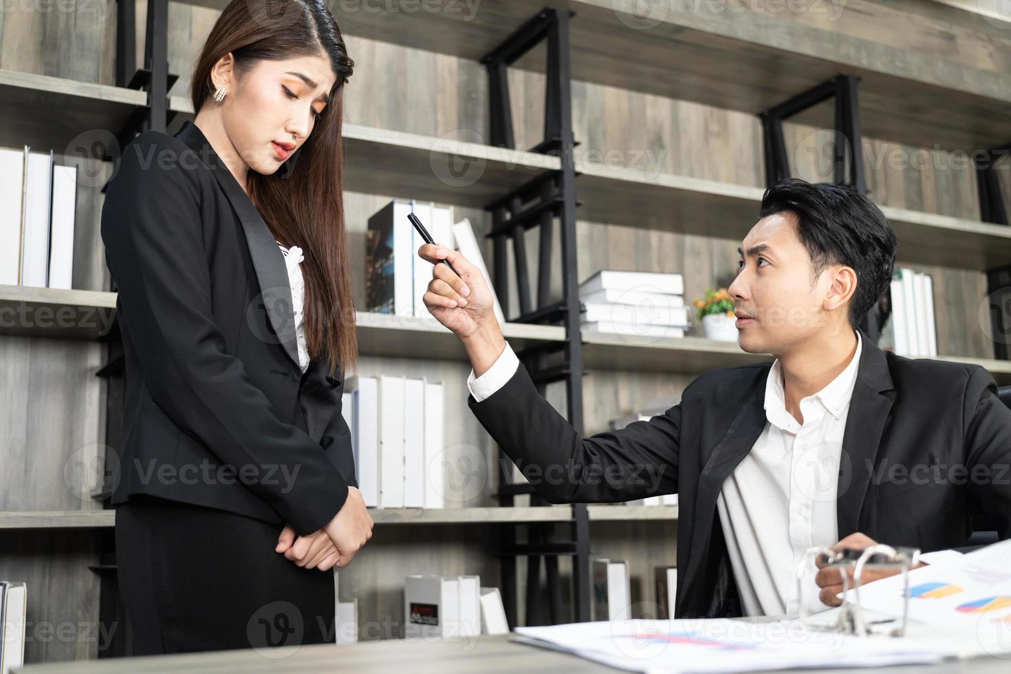 un patron qui poursuit ses responsabilités et une femme d'affaires qui est harcelée par le pouvoir. le patron insatisfait pointe des erreurs grossières sur le rapport critiquant le travail réprimandant accusant une employée photo