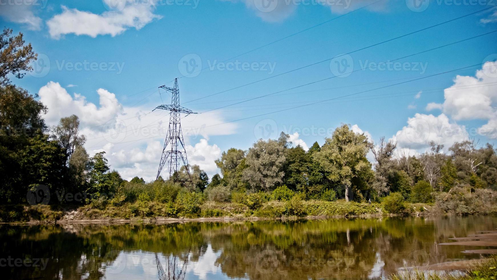 timelapse plan large de lignes électriques et de pylônes à haute tension sur un champ à la campagne en été près de la rivière photo
