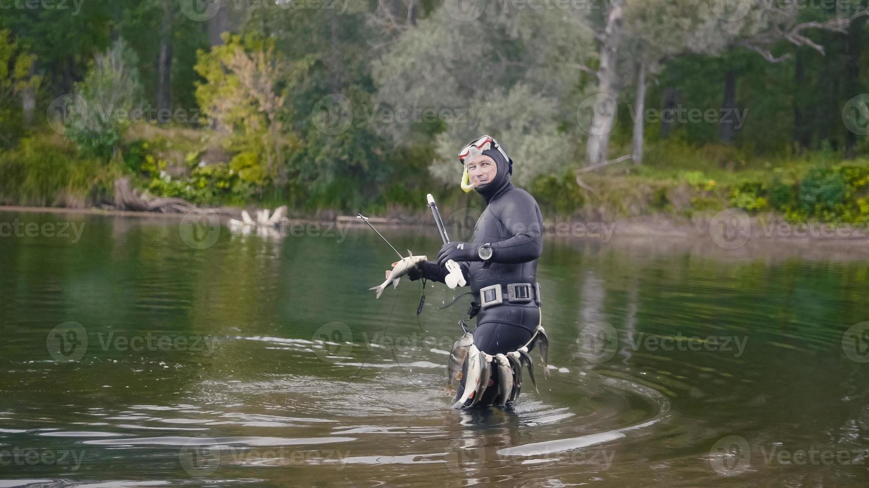 le pêcheur à la lance montre des poissons d'eau douce après avoir chassé dans la rivière de la forêt photo