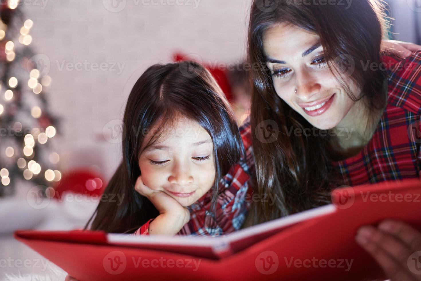 fille avec sa mère a lu un livre de Noël photo