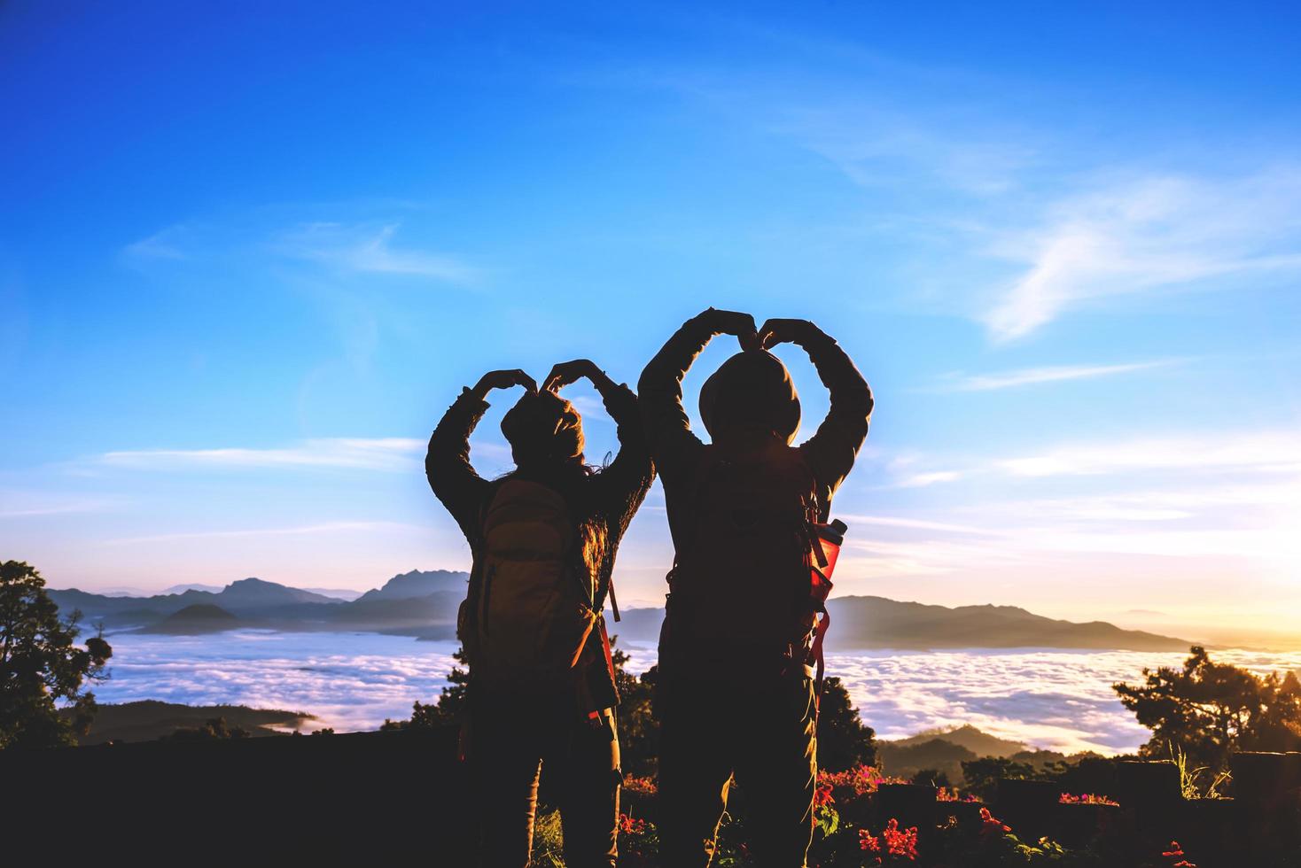 amoureux des femmes et des hommes asiatiques voyagent se détendre pendant les vacances. se lever pour le lever du soleil sur la montagne photo