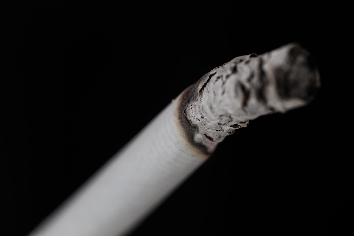 cigarette allumée avec de la fumée sur fond noir photo