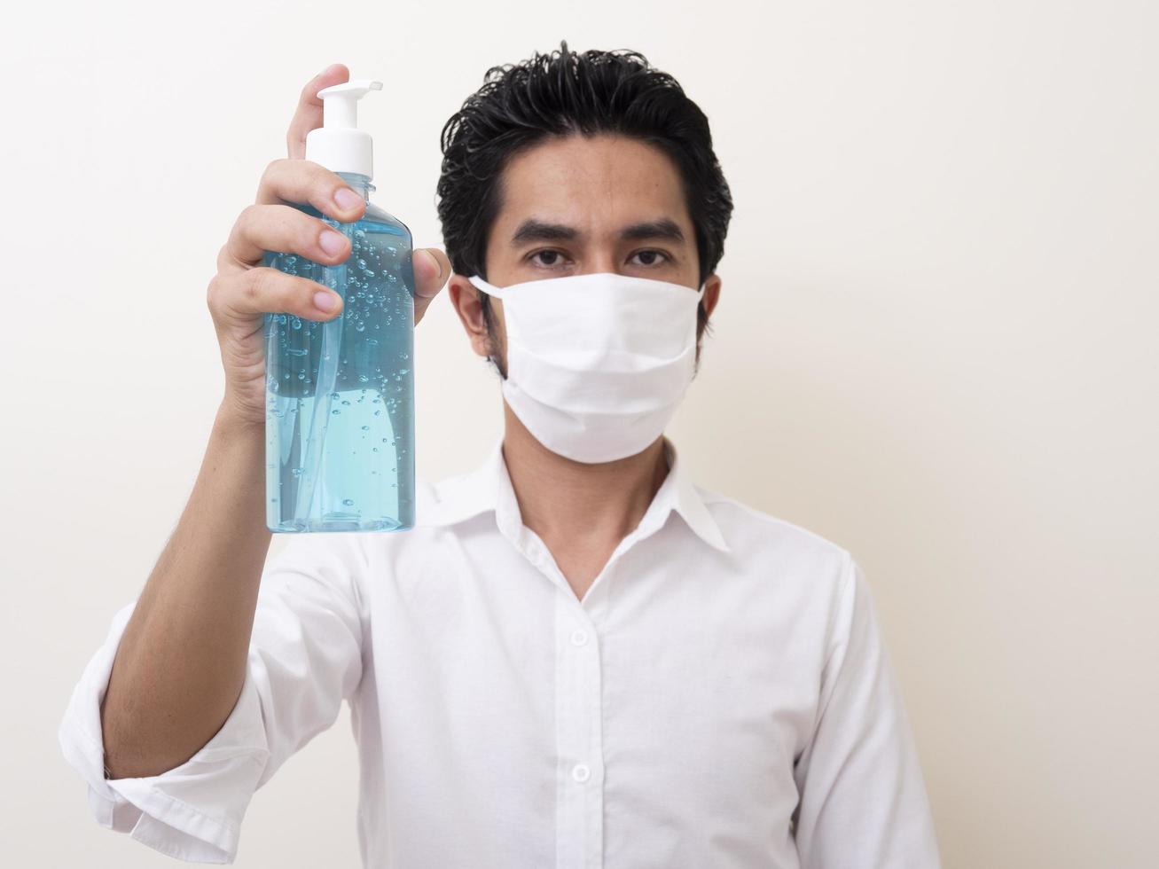 un homme portant un masque utilise actuellement du gel d'alcool pour se laver les mains photo