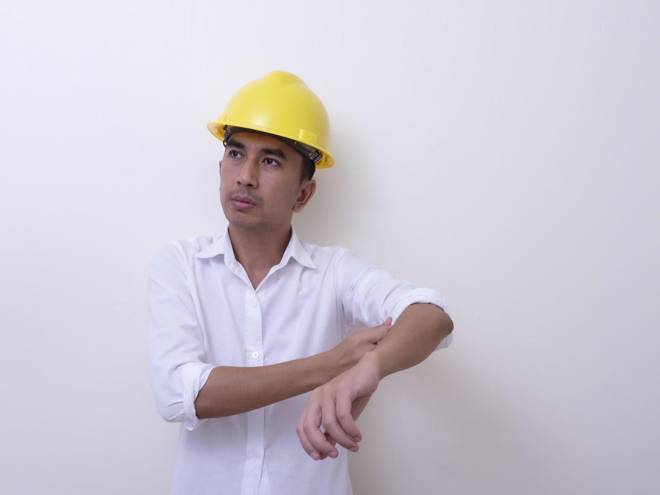 ingénieur avec les mains croisées portant un casque jaune sur fond blanc photo