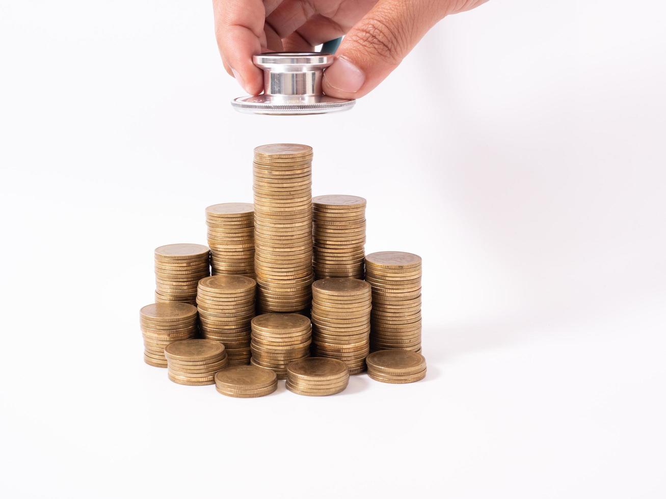 stéthoscope sur pile de pièces, sur fond blanc. argent pour les soins de santé, aide financière, concept photo