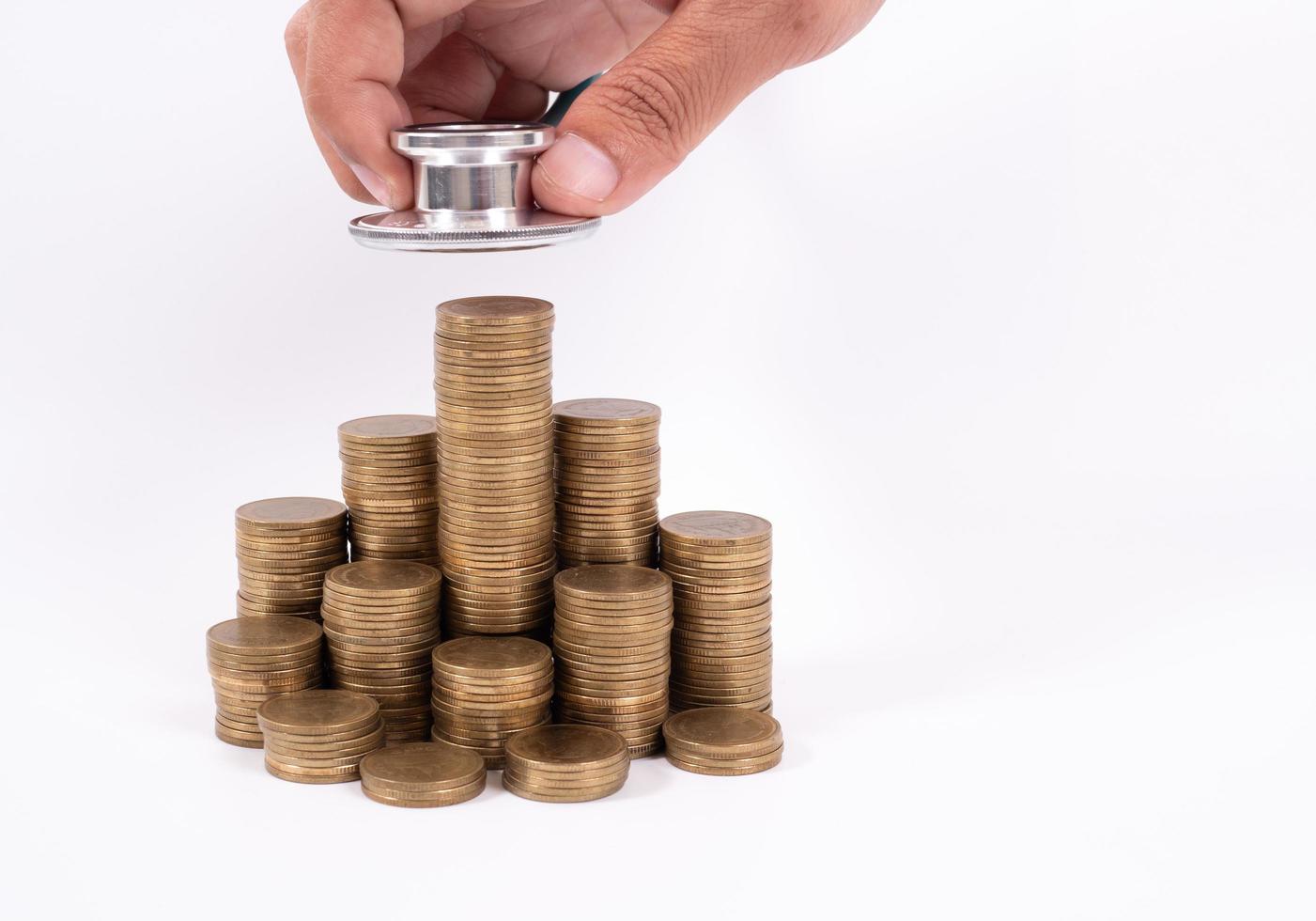 stéthoscope sur pile de pièces, sur fond blanc. argent pour les soins de santé, aide financière, concept photo