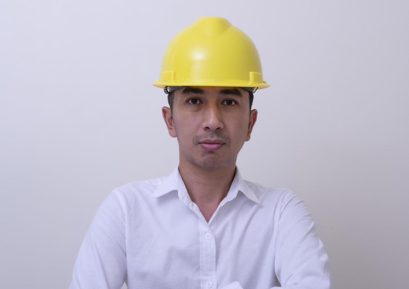 ingénieur avec les mains croisées portant un casque jaune sur fond blanc photo