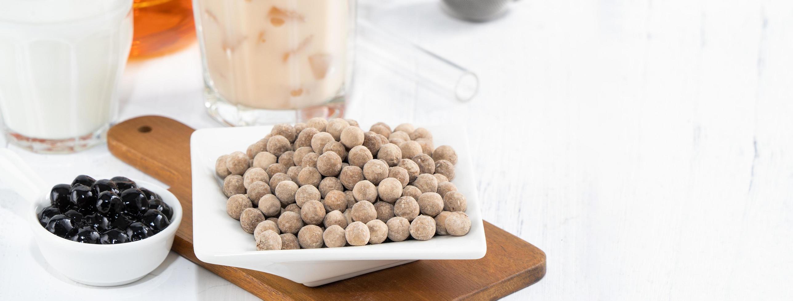 thé au lait à bulles avec ingrédient de garniture de perles de tapioca, célèbre boisson taïwanaise sur fond de table en bois blanc dans un verre à boire, gros plan, espace de copie photo