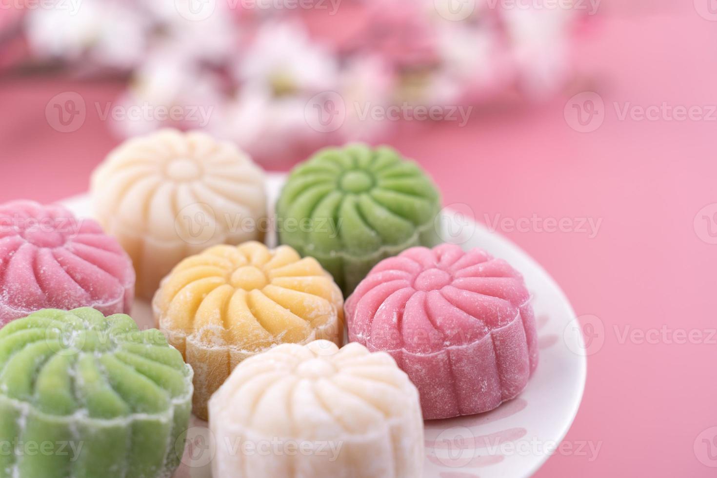 gâteau de lune coloré en peau de neige, gâteau de lune enneigé sucré, dessert salé traditionnel pour le festival de la mi-automne sur fond rose pâle pastel, gros plan, style de vie. photo