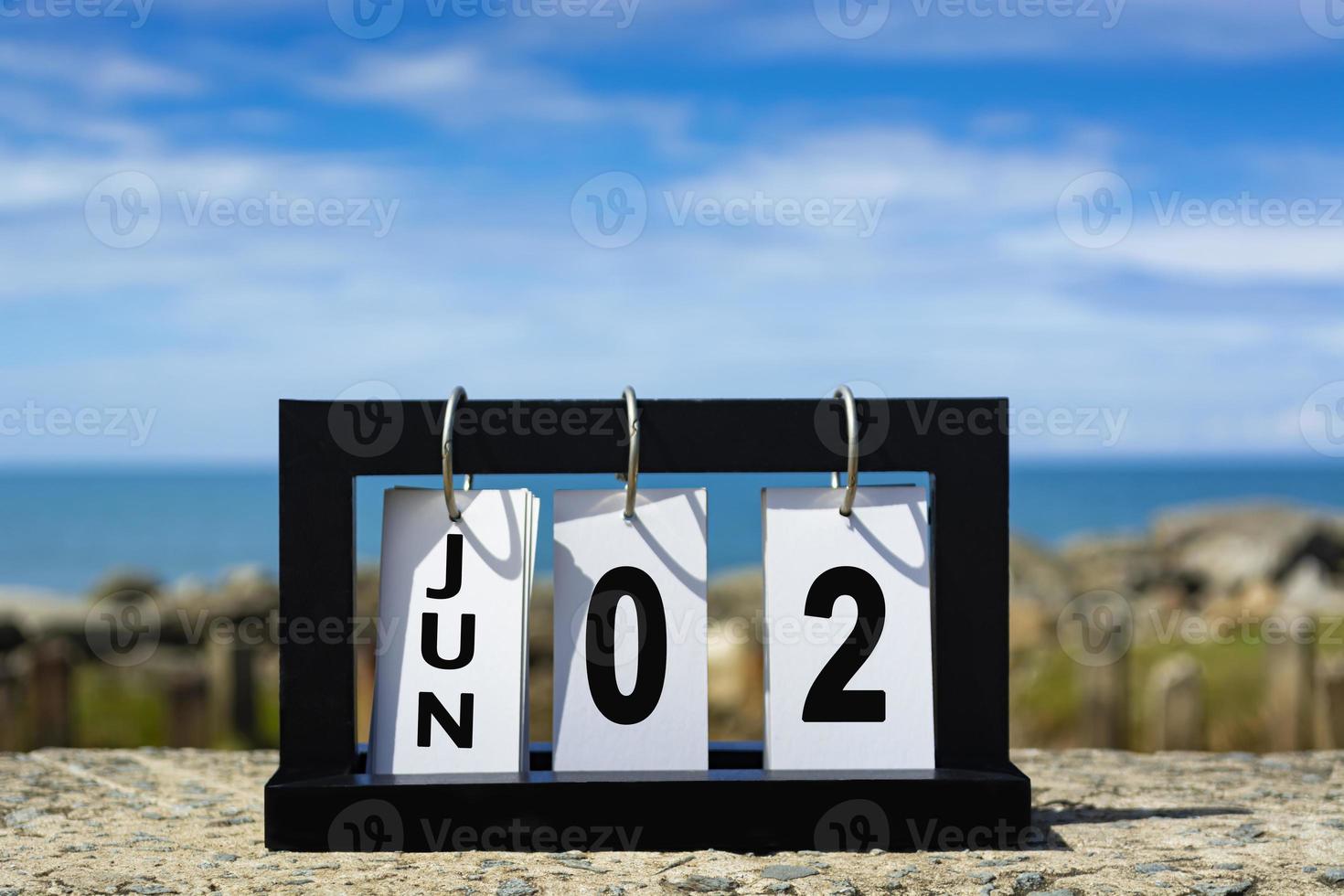 juin 02 calendrier date texte sur cadre en bois avec arrière-plan flou de l'océan. photo