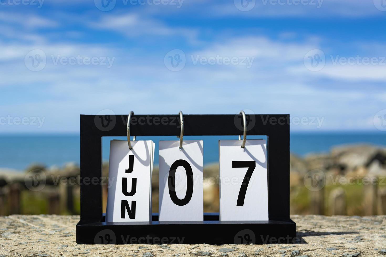 juin 07 texte de la date du calendrier sur cadre en bois avec arrière-plan flou de l'océan. photo