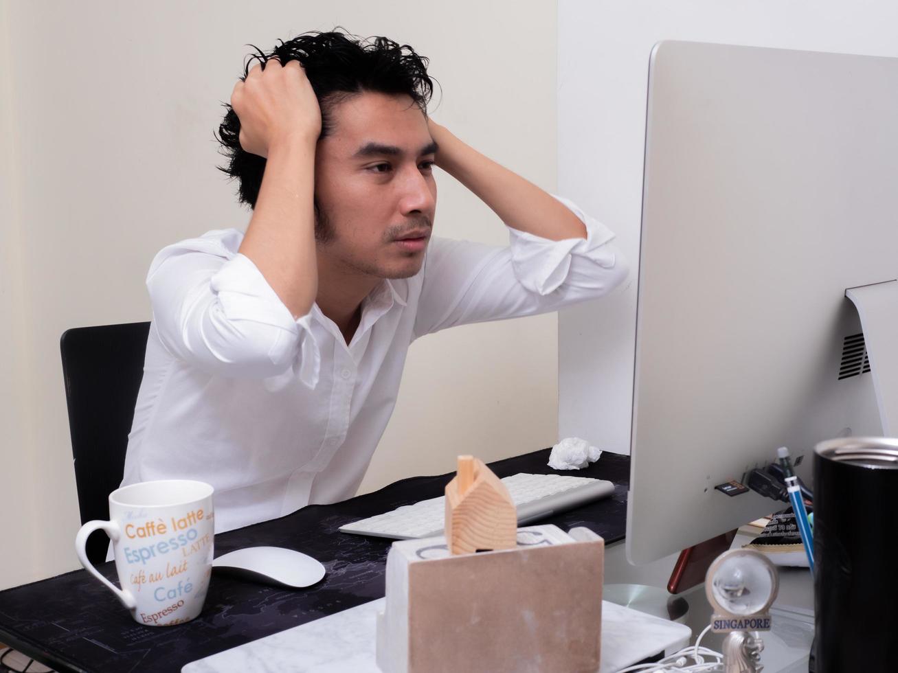 un homme asiatique sérieux travaille avec un ordinateur portable dans la chambre de son appartement dans le concept de travail à domicile et de travail à domicile photo