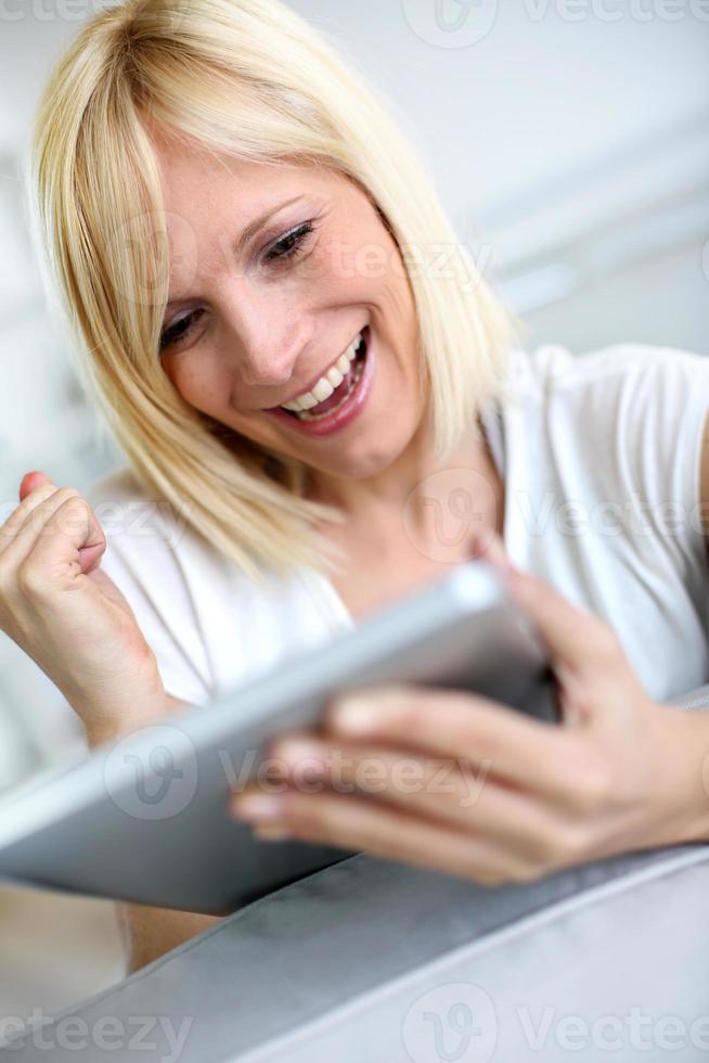 expression positive pour une femme blonde à l'aide d'une tablette numérique photo