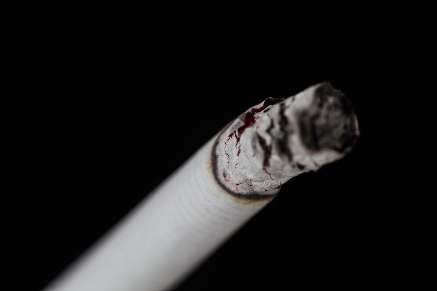 cigarette allumée avec de la fumée sur fond noir photo