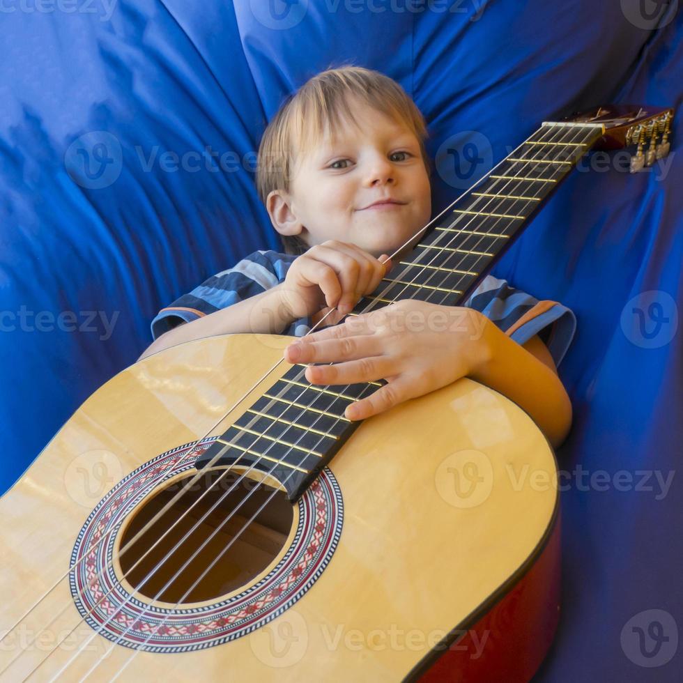 petit garçon joue de la guitare et chante sur le balcon photo