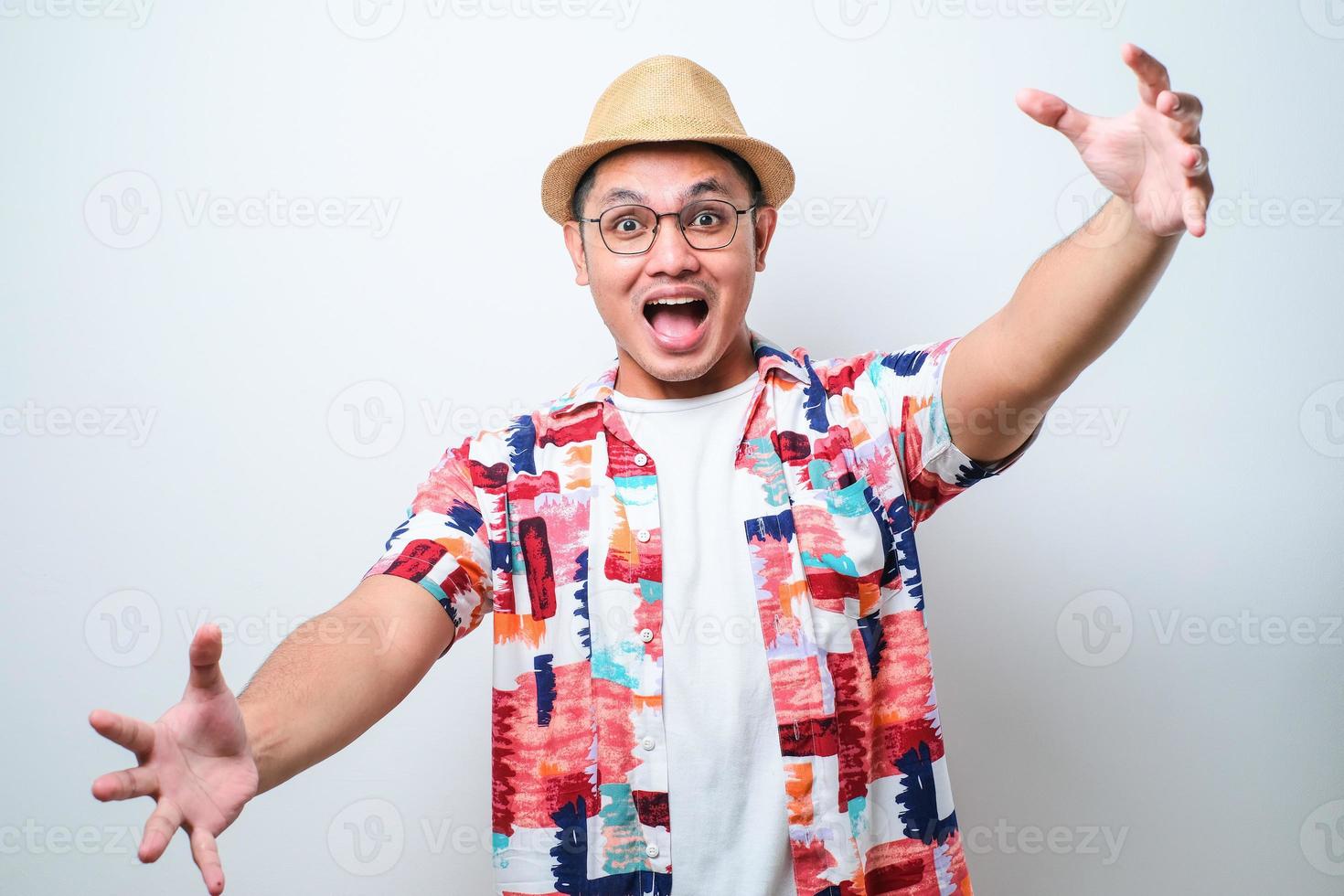 jeune bel homme asiatique portant une chemise de plage décontractée regardant la caméra en souriant à bras ouverts pour un câlin. photo