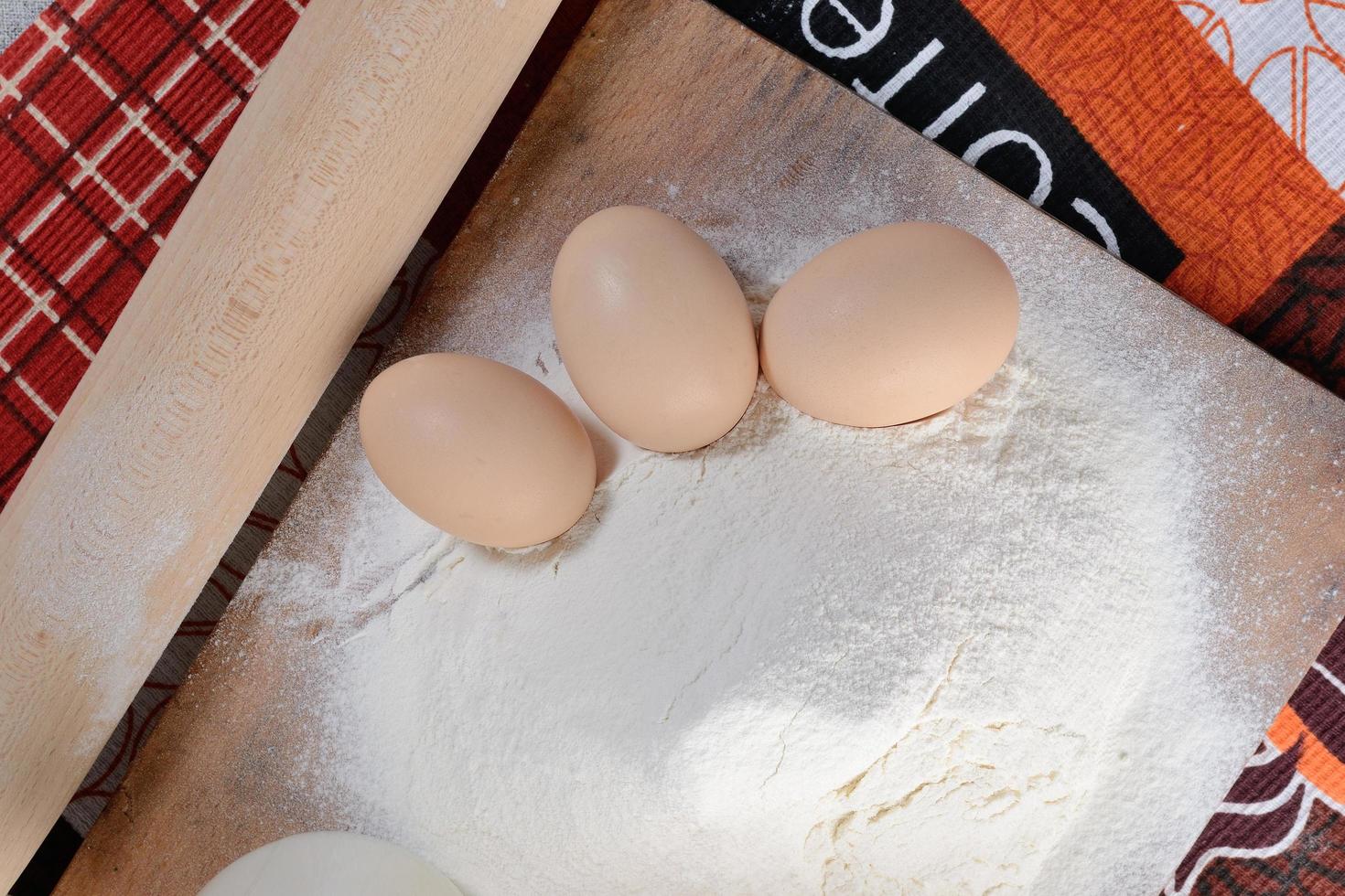 trois œufs de poule sur une planche à découper avec de la farine photo