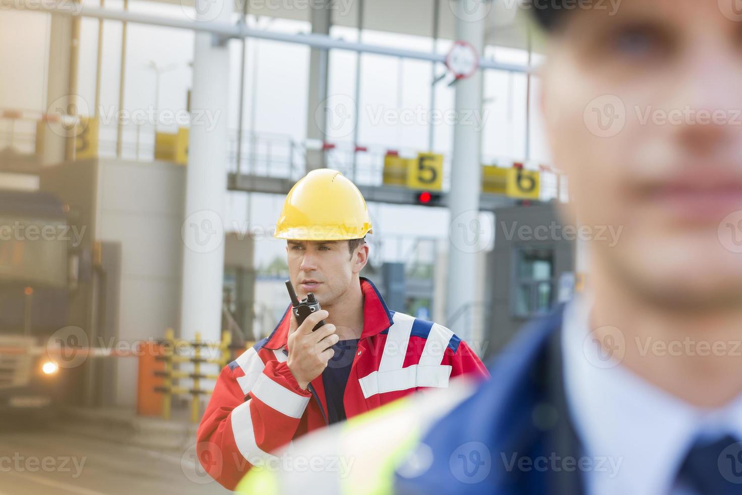 Travailleur de sexe masculin à l'aide de talkie-walkie avec un collègue au premier plan au chantier naval photo