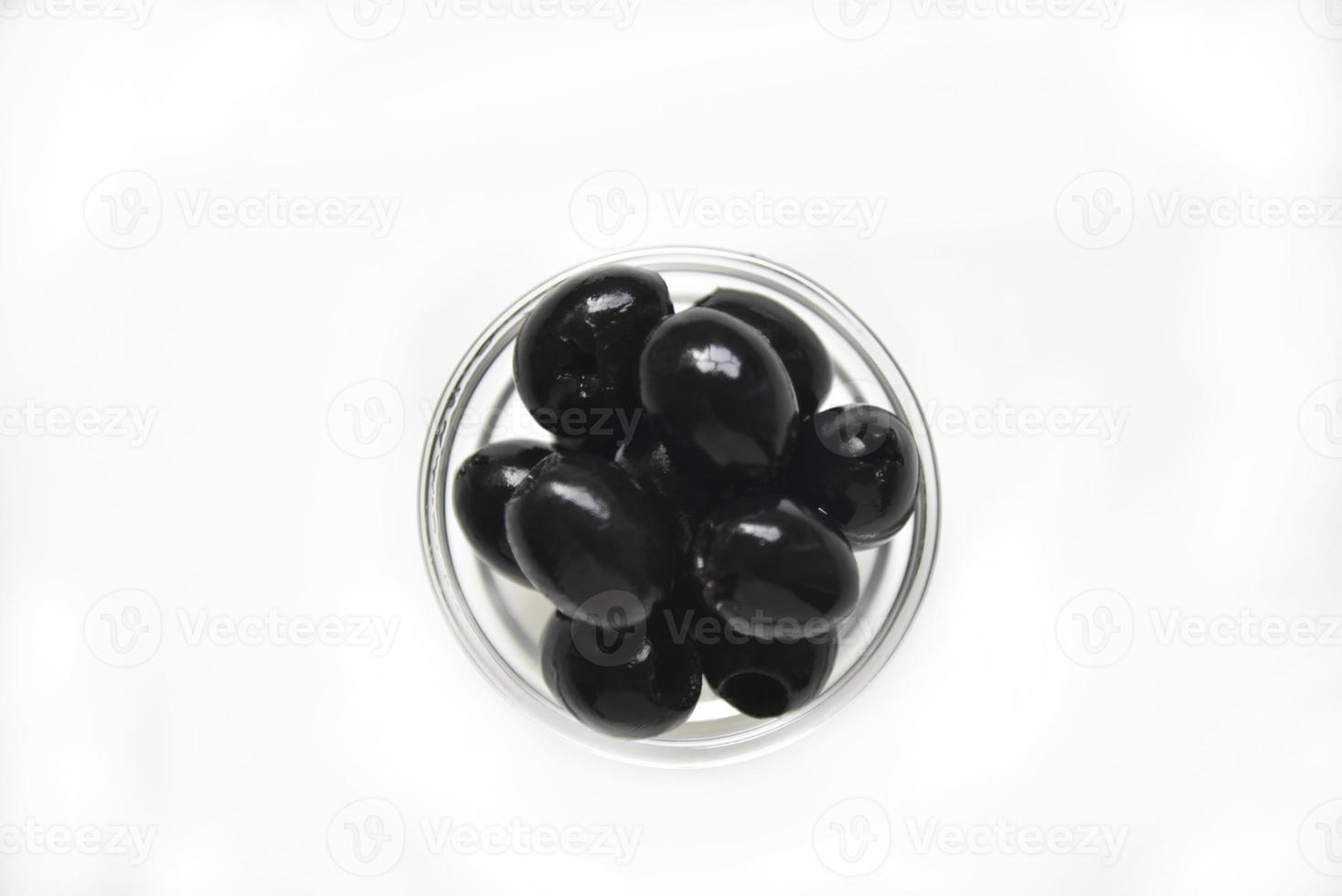 olives noires dans une casserole blanche et en verre sur fond blanc. photo