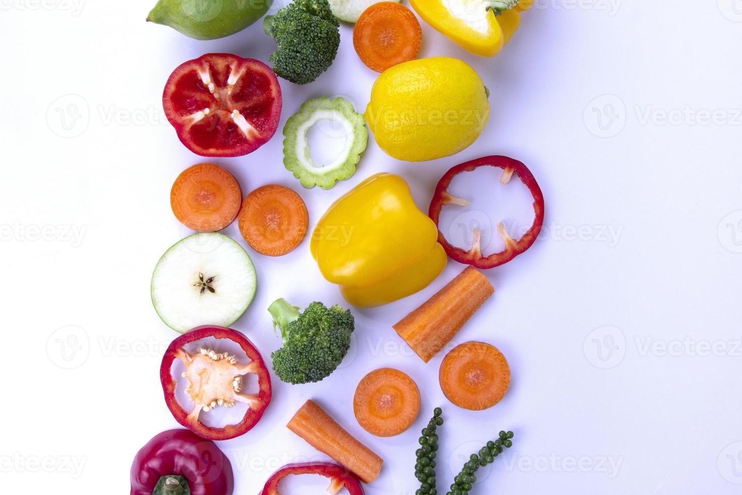nourriture mélangée saine en position centrale sur fond blanc, fruits et légumes végétariens frais et sains, brocoli, coupe de piment doux, carotte, poivrons verts et citron photo