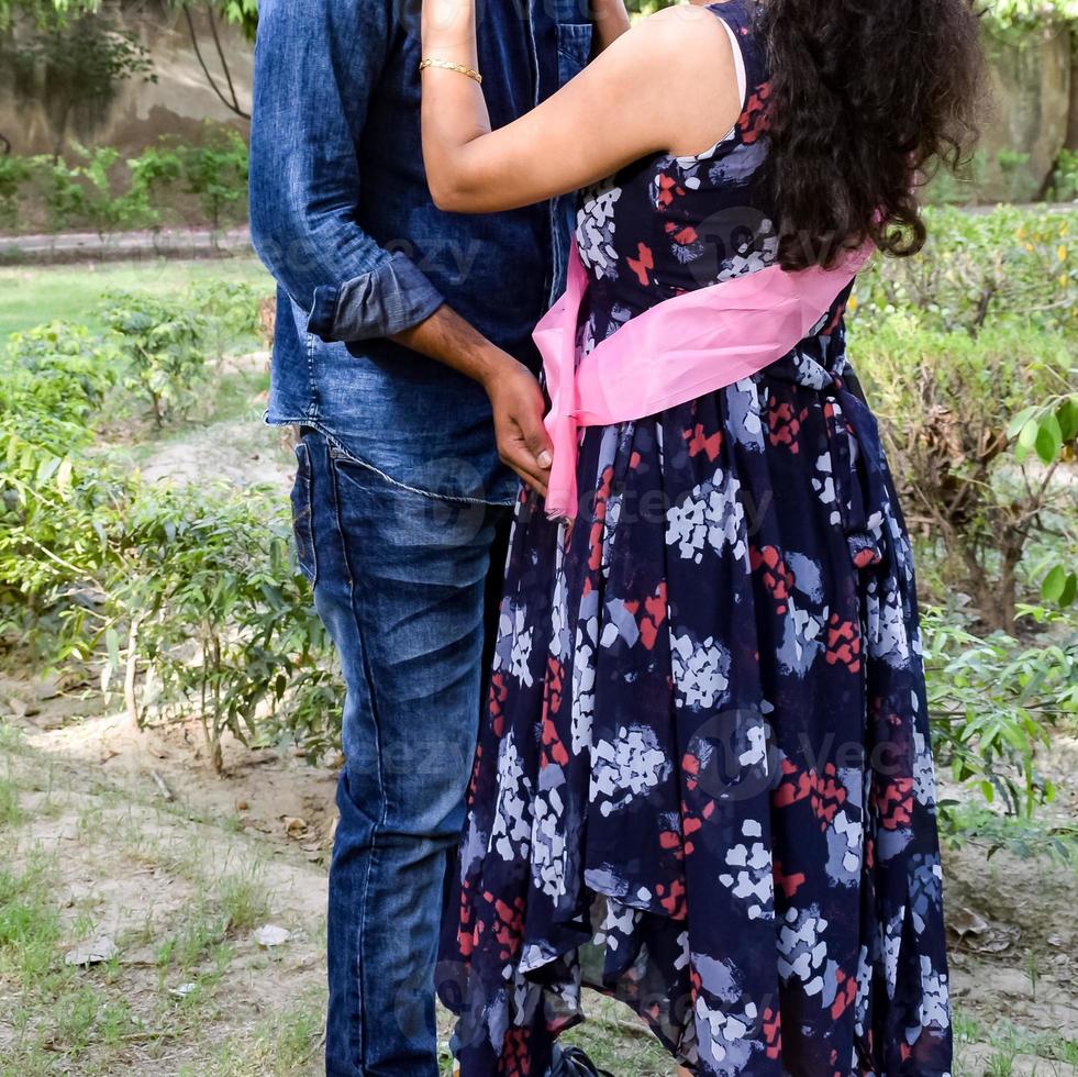 couple indien posant pour une séance photo de maternité. le couple pose dans une pelouse avec de l'herbe verte et la femme étale sa bosse de bébé dans le jardin de lodhi à new delhi, inde