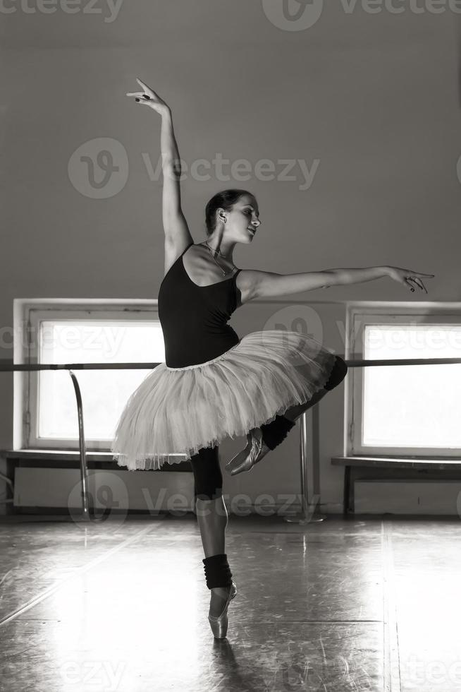 une charmante ballerine en body pose des éléments de ballet dans une coiffe dans un studio photo