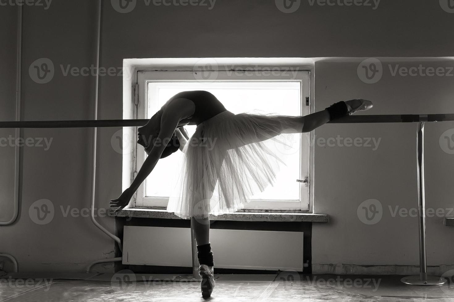 une charmante ballerine en body pose des éléments de ballet dans une coiffe dans un studio photo