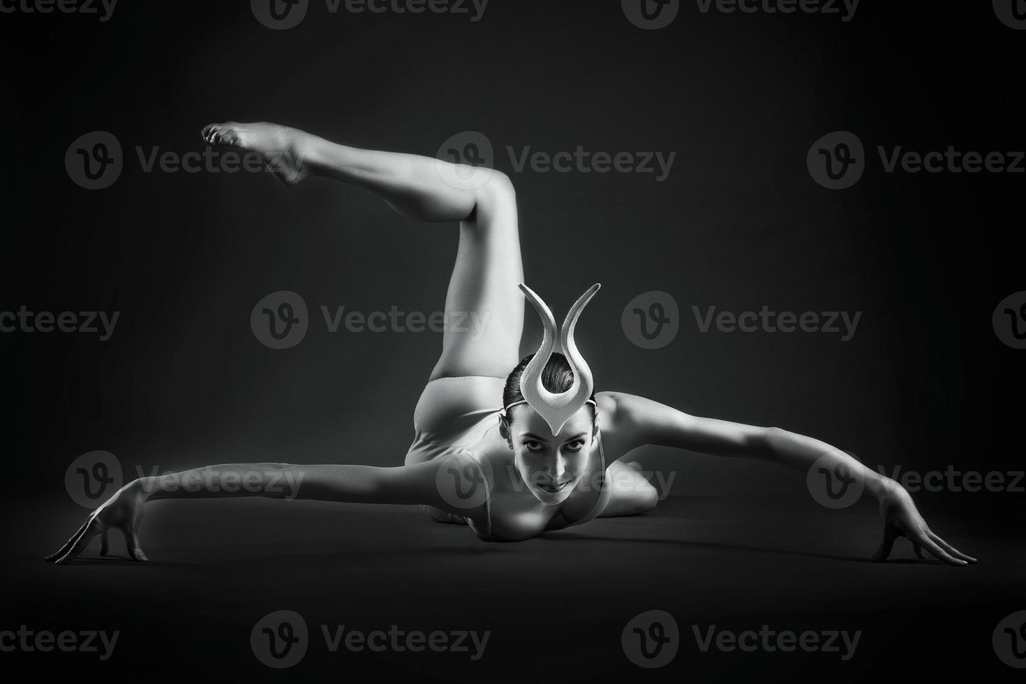 une charmante ballerine en body pose des éléments de ballet dans une coiffe dans un studio photo