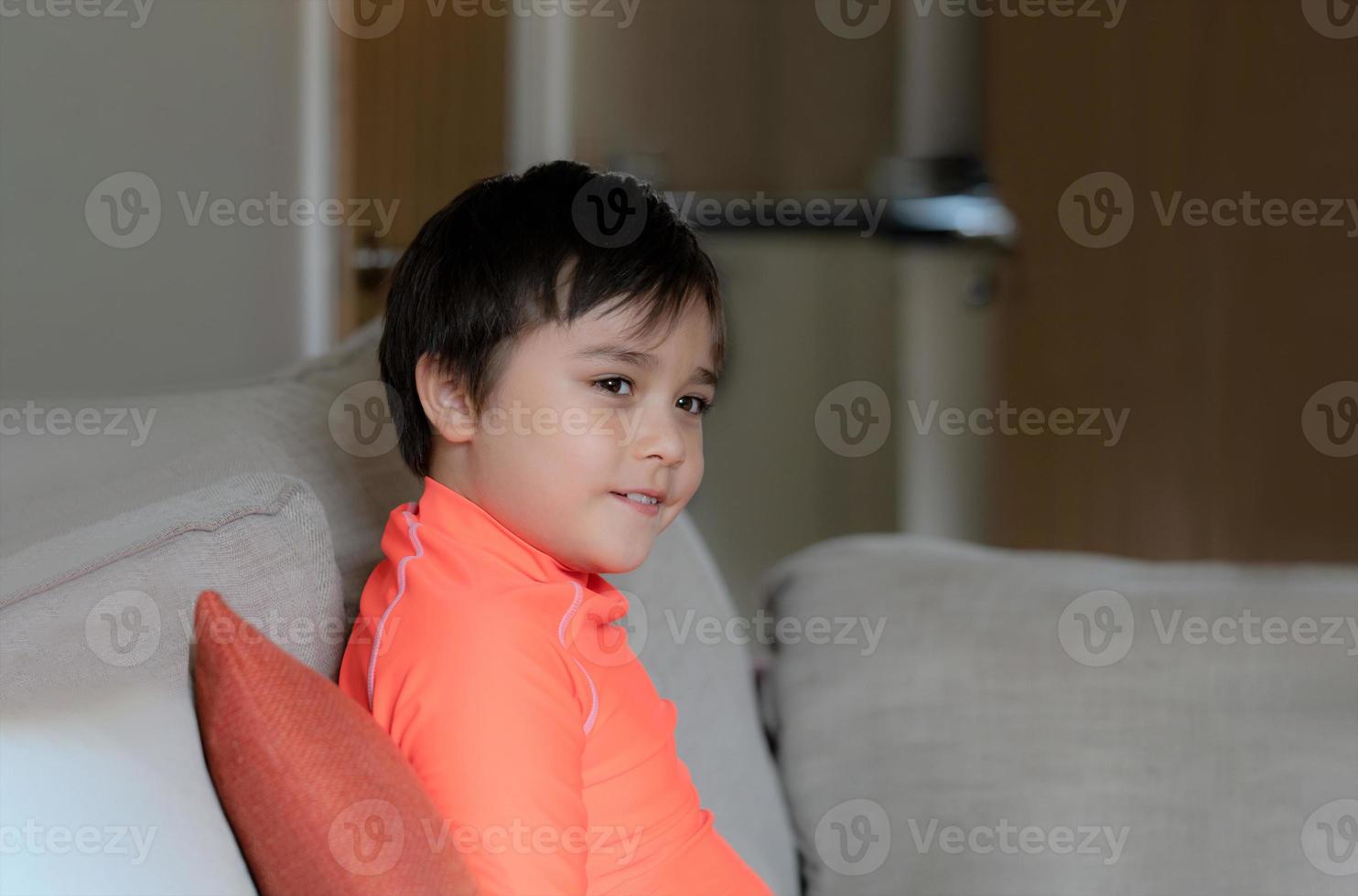 portrait enfant en maillot de bain, heureux jeune garçon assis sur un canapé regardant avec un visage souriant. enfant se relaxant dans le salon préparez-vous à aller nager. concept d'enfants en bonne santé photo