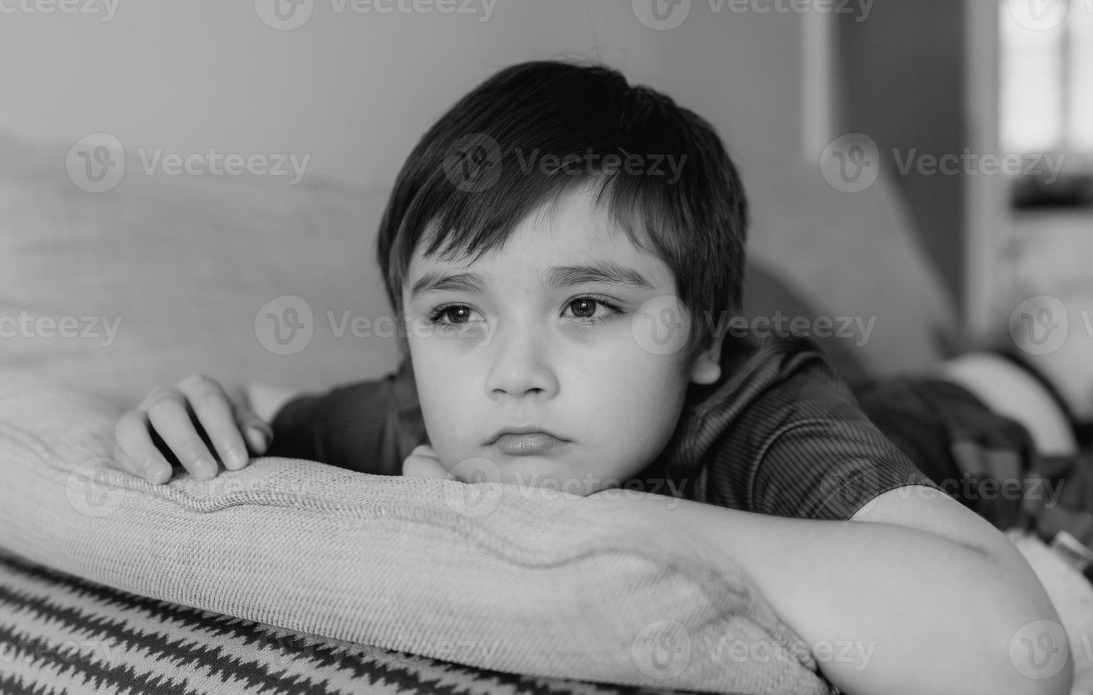 portrait noir et blanc enfant visage ennuyé regardant profondément dans ses pensées, garçon solitaire avec un visage pensant assis seul sur un canapé, enfant d'âge préscolaire bouleversé avec un visage malheureux ou triste, enfants gâtés, santé mentale photo