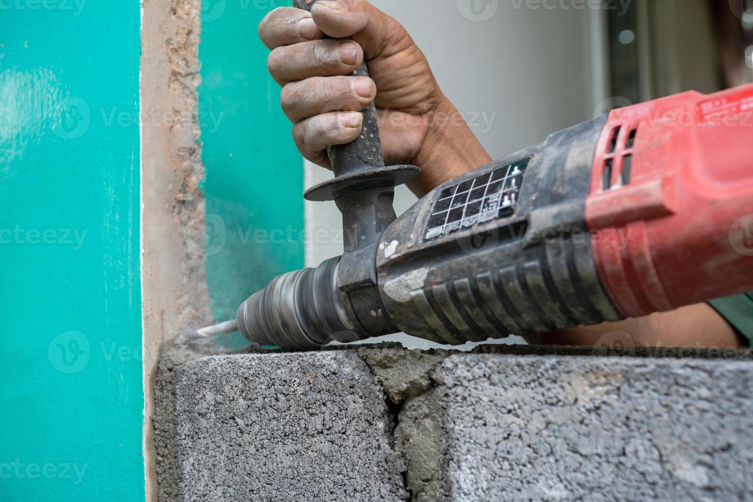 les techniciens utilisent une perceuse pour percer des trous dans la maçonnerie afin de renforcer la structure de la construction. photo