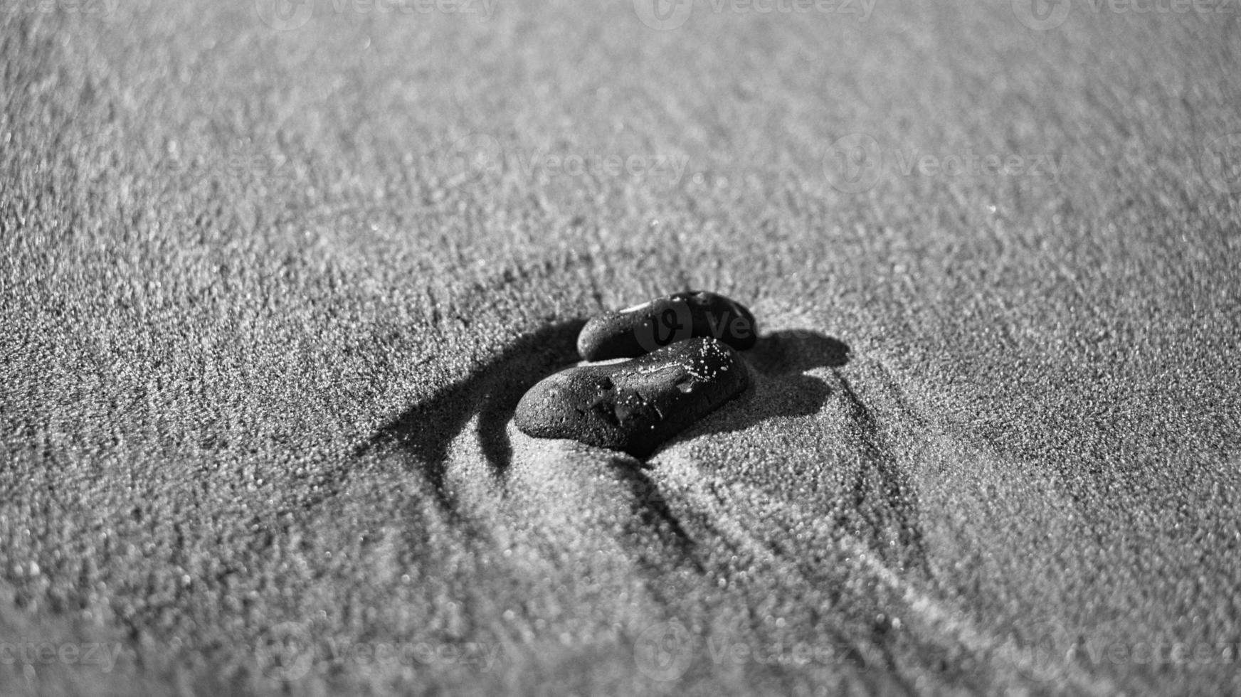 pierre en forme de coeur dans le sable de la plage sur la mer baltique en noir et blanc. photo