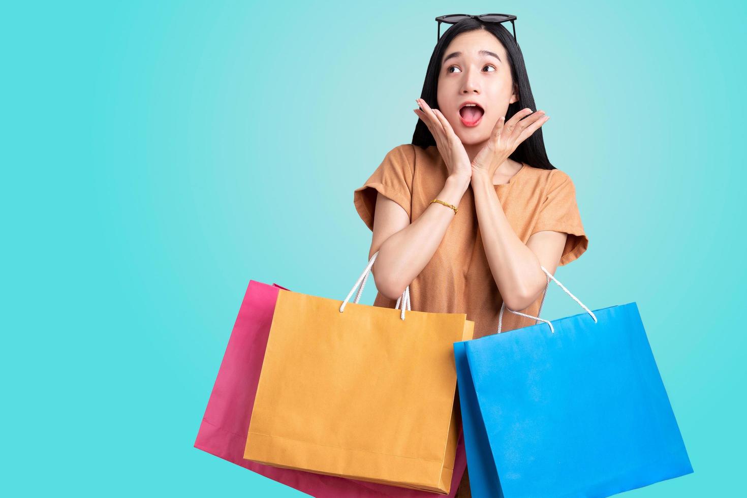 portrait femme asiatique portant des sacs à provisions colorés sur fond bleu isolé , concept de vente d'été , jeune femme aime faire du shopping photo