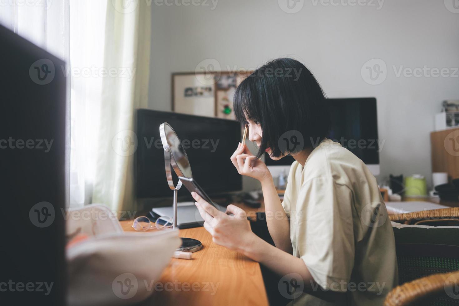 jeune femme adulte asiatique maquillage et soin du visage à l'aide d'un téléphone portable pour diffuser le créateur de contenu à la maison. photo