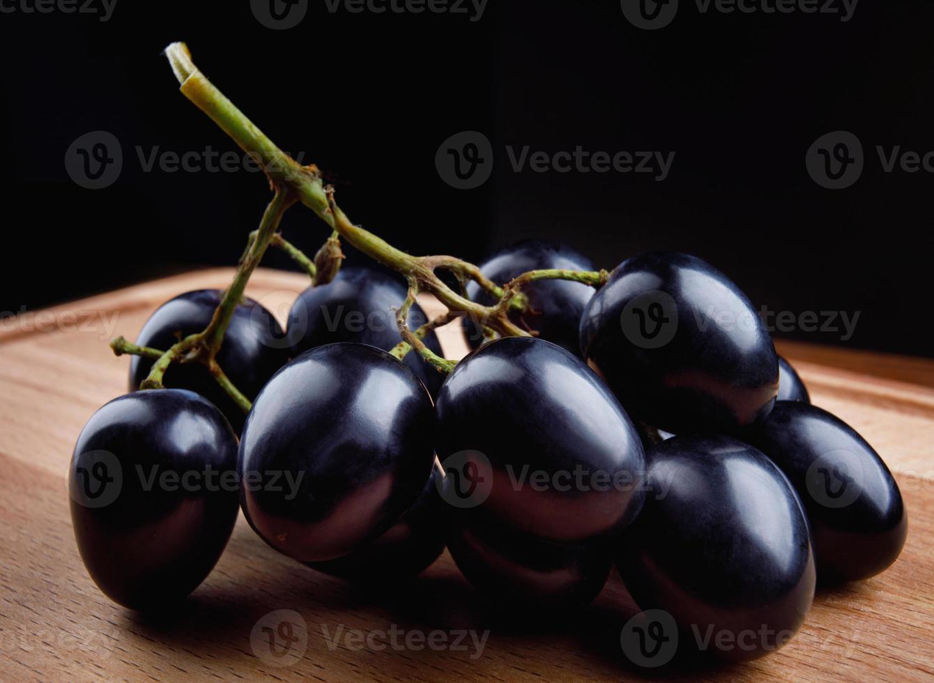 une petite grappe de raisins noirs sur une planche de bois. photo