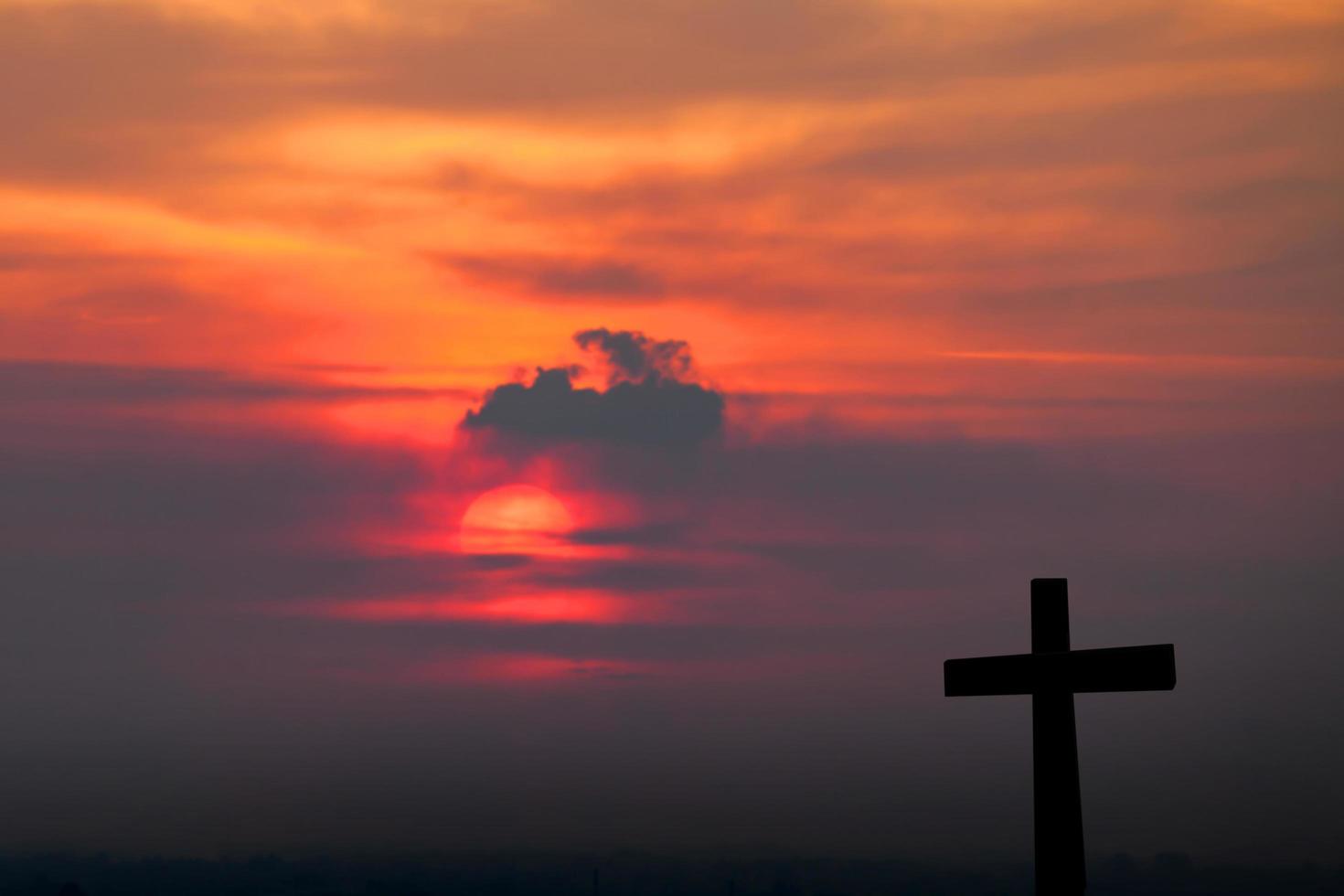 silhouette de croix sur fond de coucher de soleil flou photo