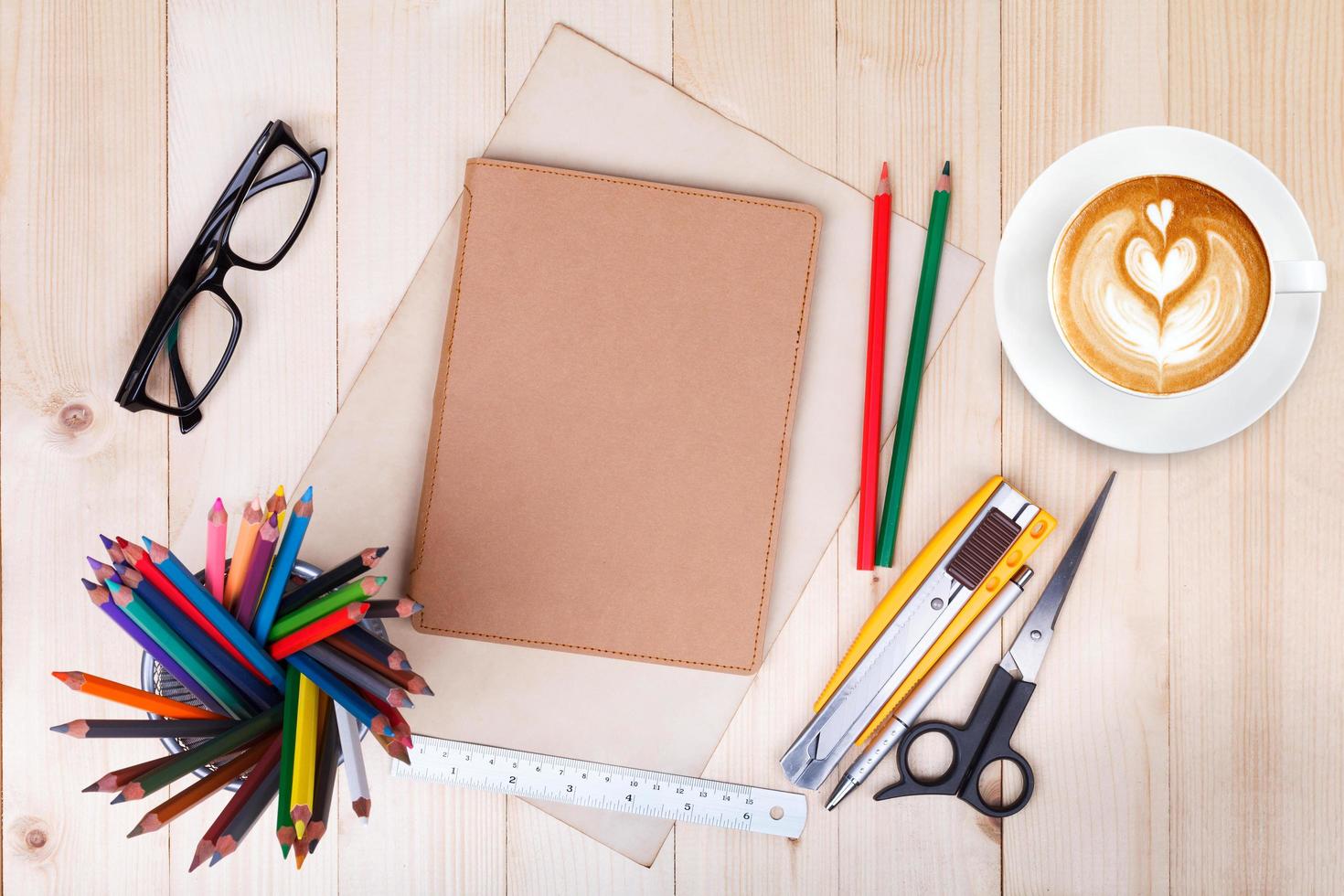 cahier vierge avec des crayons de couleur, des stylos et une tasse de café sur une table en bois photo