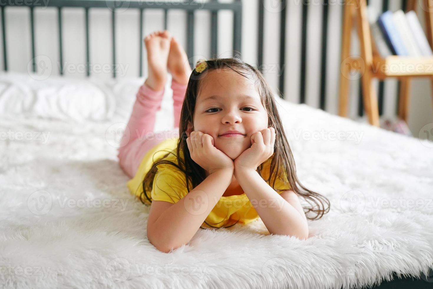 petite fille allongée sur le lit et regarde la caméra. photo