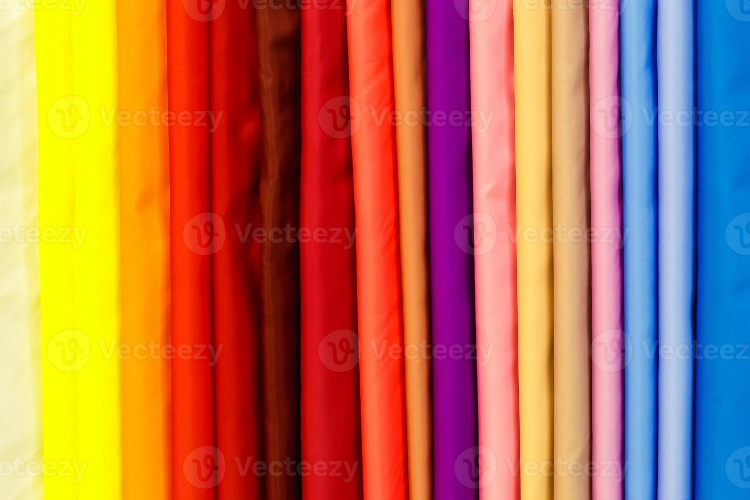 Large sélection de vêtements de tissus de soie textile de couleur différente en rangée dans un magasin de draperies photo