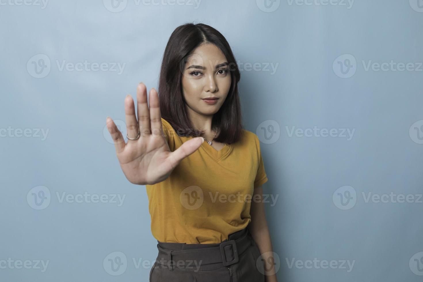 jeune femme asiatique portant un t-shirt décontracté sur fond bleu isolé faisant un panneau d'arrêt avec la paume de la main. photo