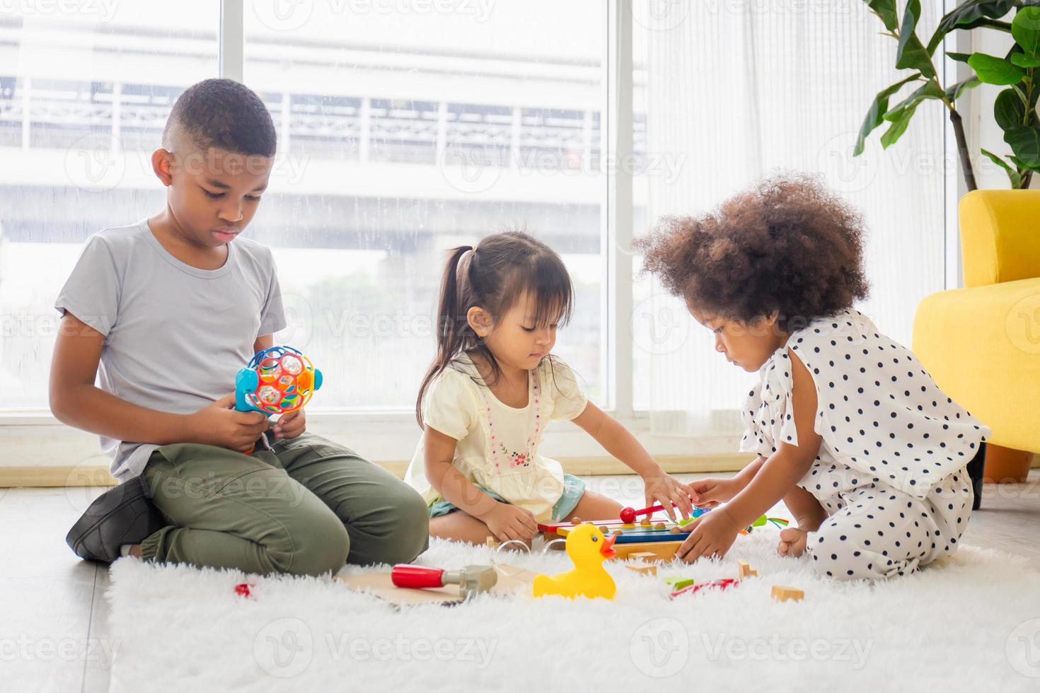 enfants jouant avec leurs amis sur le sol, enfants filles et garçons jouant à des jouets et à des jeux dans le salon photo