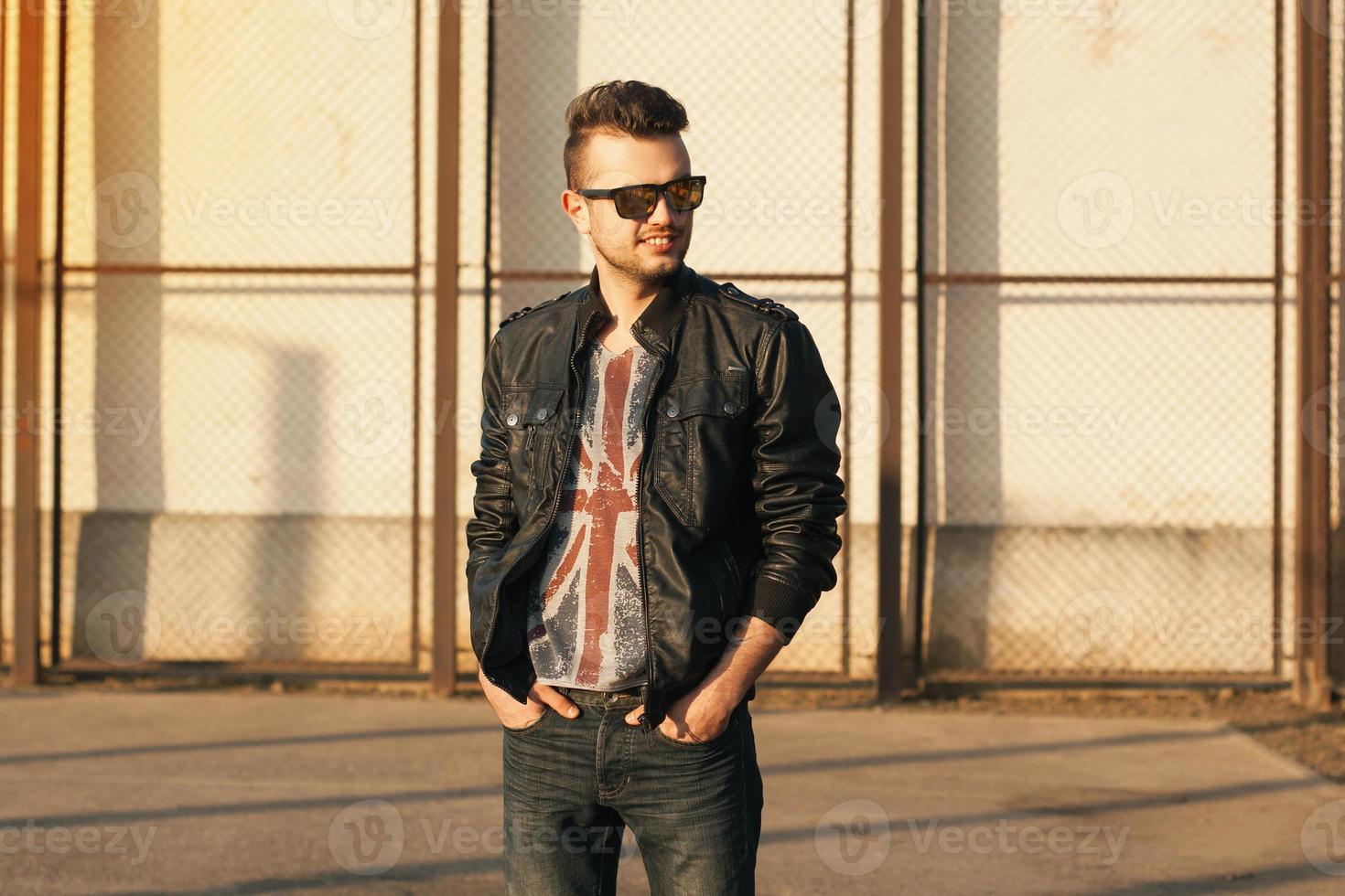 hipster dans une veste en cuir noire et des lunettes de soleil. portrait de coucher de soleil en plein air. photo