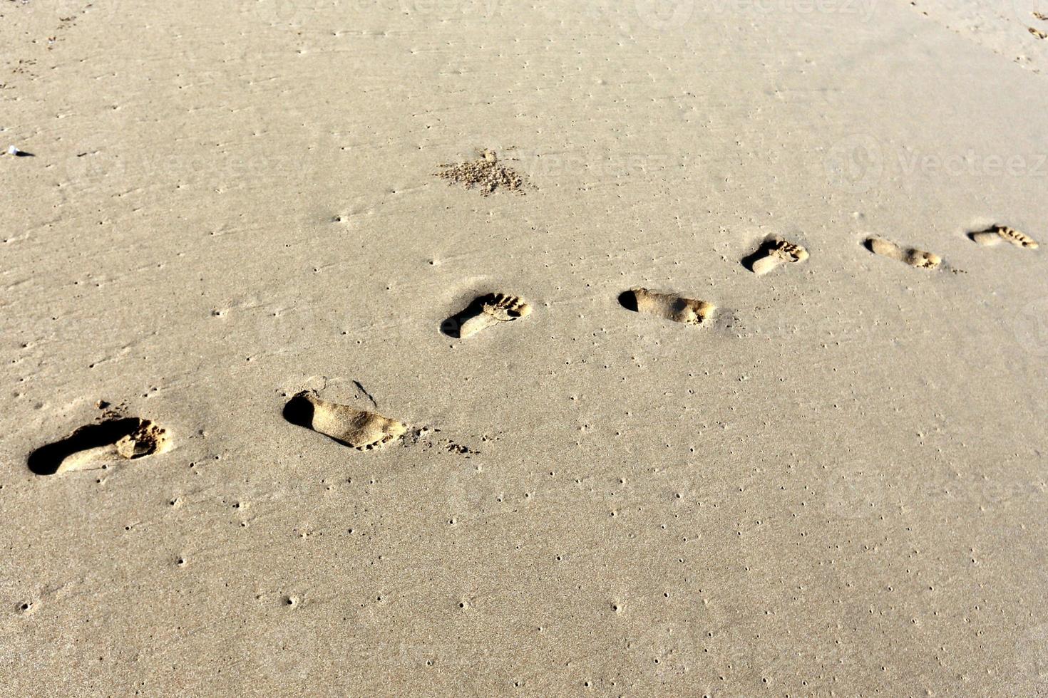 empreintes de pas dans le sable sur la plage de la ville. photo