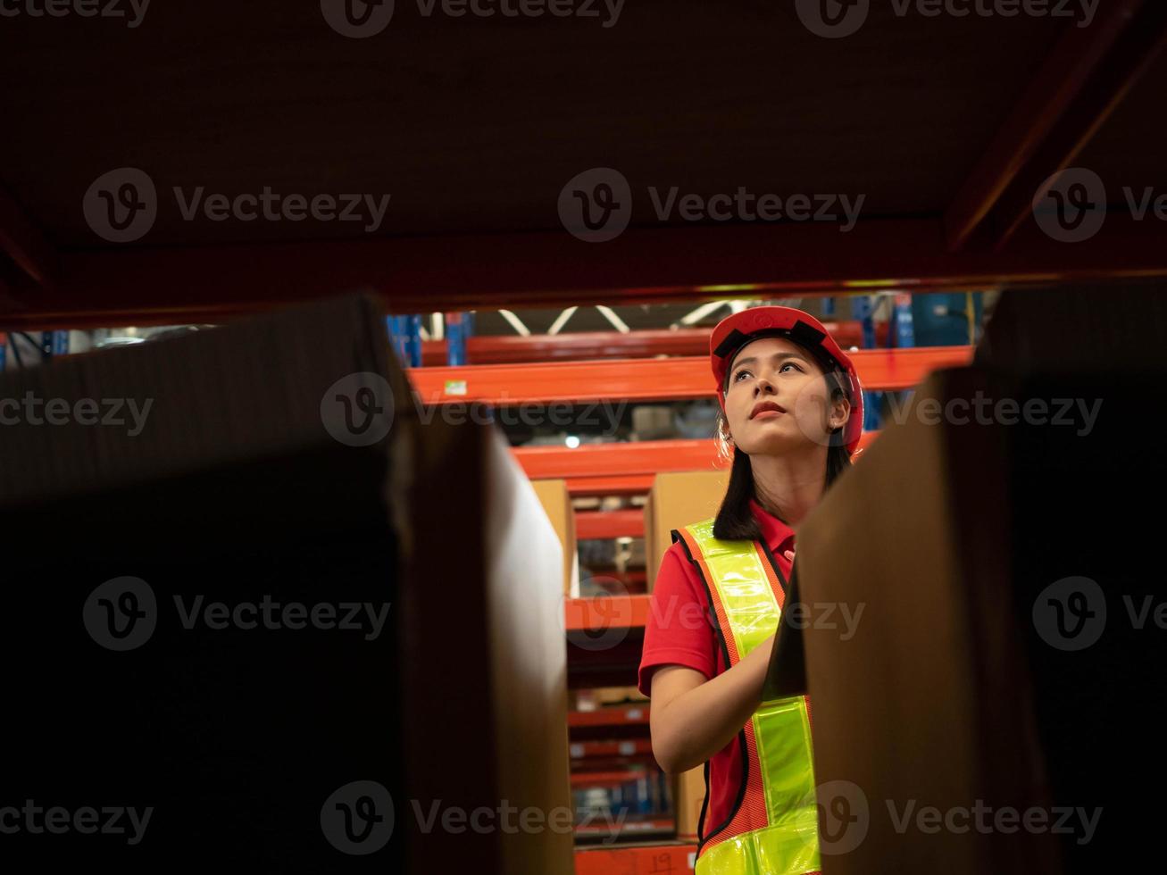 femme jeune adulte asiatique personne orange jaune casque casque sécurité personnel est debout liste de contrôle rapport ordre presse-papiers logistique cargaison entrepôt import export intérieur usine étagère travail emploi carrière photo