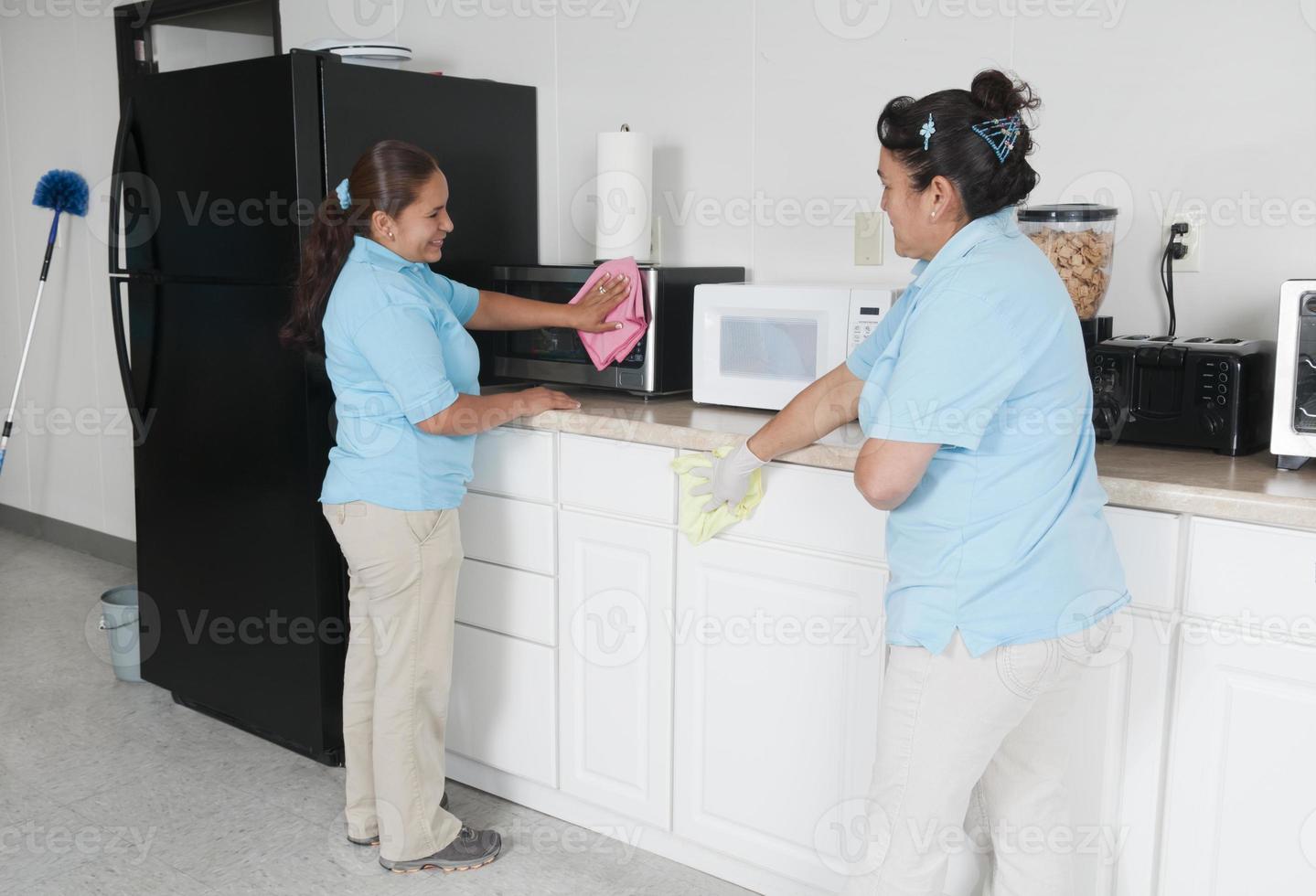 deux femmes de ménage nettoyant une salle de pause d'entreprise photo