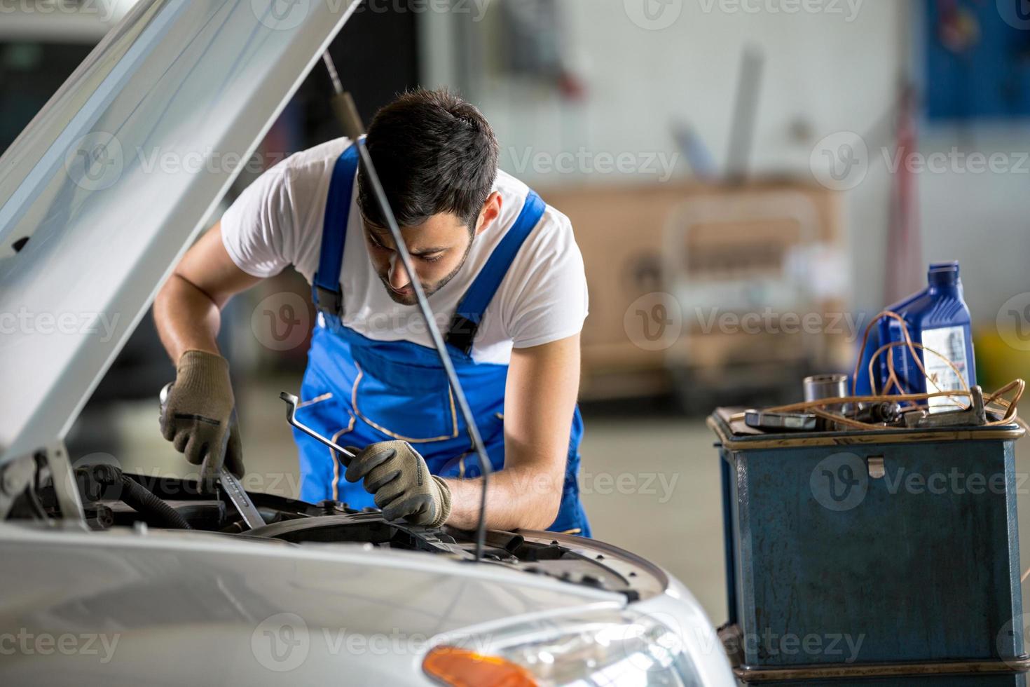 mécanicien automobile travaillant sous le capot photo