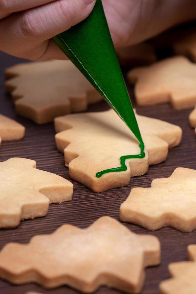 gros plan sur le dessin d'un biscuit au sucre d'arbre de noël sur fond de table en bois avec glaçage. photo