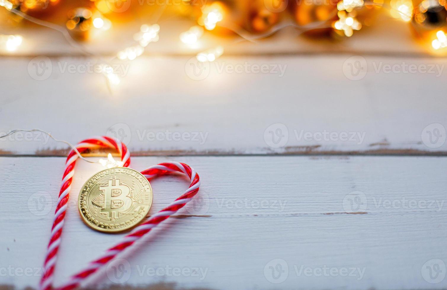 pièce de monnaie bitcoin au coeur du caramel de canne en bonbon avec des guirlandes lumineuses et de la neige. noël, carte de voeux de nouvel an. crypto-monnaie, finance, richesse et investissement. copie espace photo