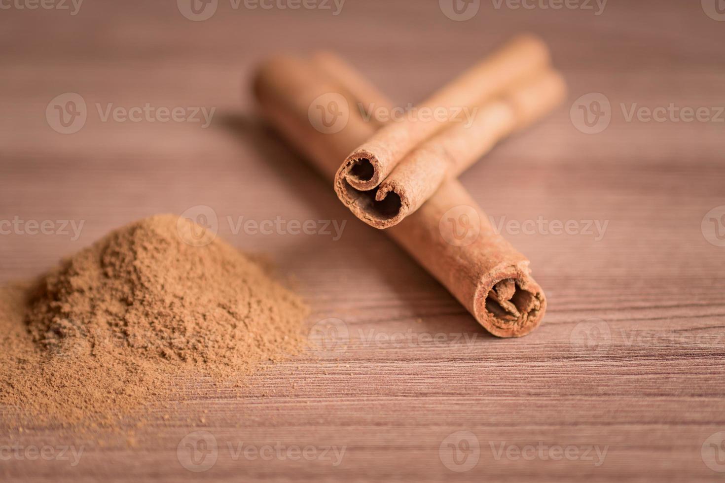 bâtons de cannelle et poudre sur table en bois. photo