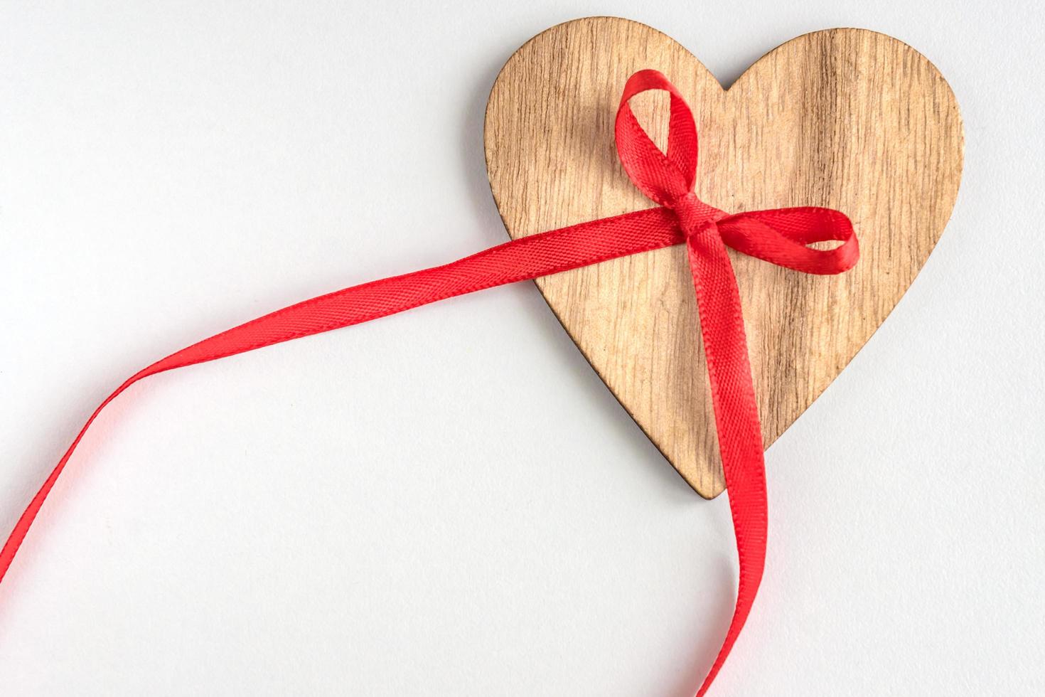 coeur en bois avec noeud de ruban rouge sur fond blanc photo